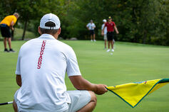 An IUK male golfer lines up a shot on the green.